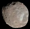 Nærbilde av den uregelmessige, kraterfylte månen Phobos mot svart bakgrunn.