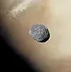 Den uregelmessige, grå månen Phobos foran Mars’ lysebrune overflate.