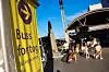 Gult skilt med «Buss for tog» ved en travel togplattform, med reisende og tog i bakgrunnen.