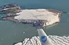 Flyfoto av en snødekt, nyoppdaget øy i havet, sett over flyvingen.