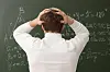 Elev sett bakfra med hendene på hodet foran en tavle med matematikk.
