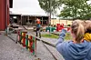 Et barn står i forgrunnen og ser mot et inngjerdet uteområde ved en gårdsbarnehage.