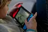 Nærbilde av et barn som spiller på en Nintendo Switch innendørs.