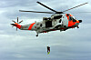 Sea King-helikopter heiser en redningsmann over sjøen under en redningsøvelse.
