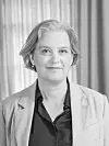 Portrett av professor Inger Skjelsbæk i lys blazer foran gardiner.