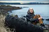Anne Carson sitter på et stort dekk ved sjøen i Reykjavík.