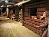 Trehus fra middelalderen som er rekonstruert inne på et museum. Til høyre står en modell av en fattig jente og tigger med en hånd utstrakt. Klærne hennes er brune. Gata er trebelagt og husene er laftet.