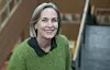 Ingvill Rasmussen smiler i en grønn strikkegenser i en innendørs trappehall.