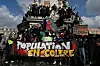 Demonstranter på en statue i Paris holder et stort banner med teksten «Population en colère».