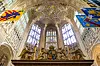 Utsmykket gotisk interiør i Westminster Abbey med viftehvelv, faner, glassmalerier og alterparti.