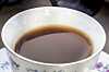 Nærbilde av svart kaffe i en hvit kopp med blomstermønster.