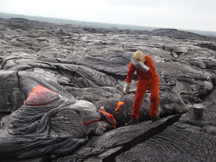 Ein geolog frå HVO skjermar ansiktet frå den intense varmen i det han tek ein prøve frå lavaen frå Kilauea, 21.oktober 2013. (Foto: U.S. Geological Survey, Hawaiian Volcano Observatory) Ein geolog frå HVO skjermar ansiktet frå den intense varmen i det han tek ein prøve frå lavaen frå Kilauea, 21.oktober 2013. (Foto: U.S. Geological Survey, Hawaiian Volcano Observatory)