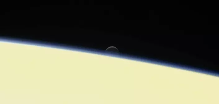 Den lille månen Enceladus går ned bak Saturn. Bildet er tatt av Cassini den 13. september, bare to dager før romsonden brant opp i de øvre lagene av Saturns tykke atmosfære. (Foto: JPL/NASA)